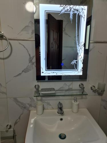 a bathroom with a white sink and a mirror at STUDIO NGOR ALAMADIES BAKU plus in Dakar