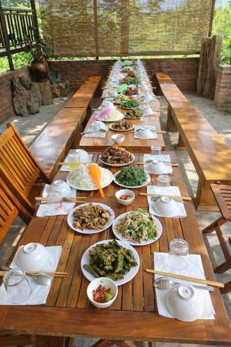 a long wooden table with plates of food on it at Thu May Homestay A Lưới in A Lưới (1)
