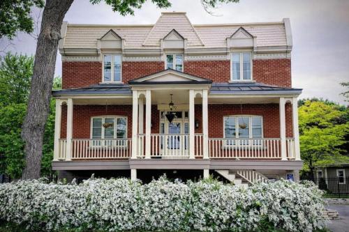 a red brick house with a white porch at Appartements Saint-Alexandre in Longueuil