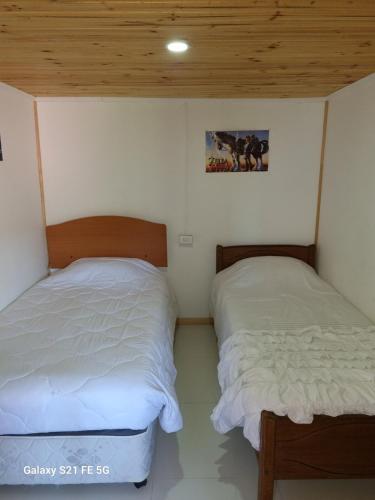 two twin beds in a room with wooden ceilings at Casa de descanso in Paredones