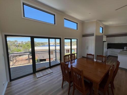a dining room with a table and chairs and windows at Moore Memories Beach House in Guilderton