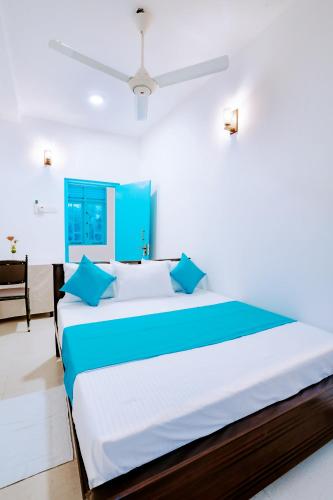 a bedroom with a large bed with blue pillows at 75 Inn Madiha in Matara