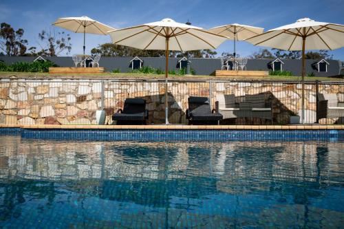 a swimming pool with two umbrellas and chairs and a pool at Clare Valley Motel in Clare