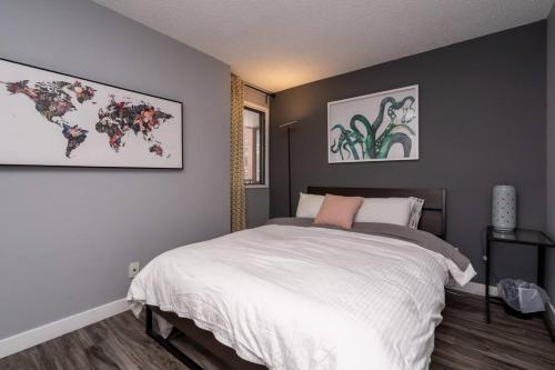 a bedroom with a large white bed and paintings on the wall at Stylish DT Condo ~2 Blocks from Stampede Grounds in Calgary