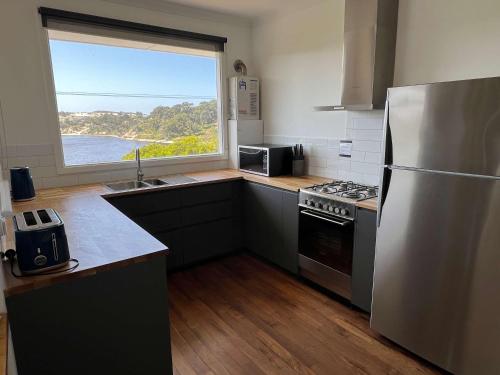 een keuken met een roestvrijstalen koelkast en een raam bij River Panorama Beach House in Guilderton