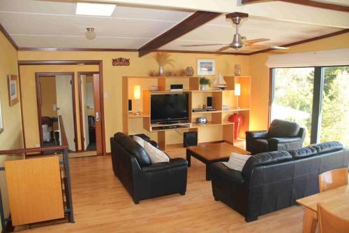 een woonkamer met twee banken en een flatscreen-tv bij Gabbadah Beach House in Guilderton