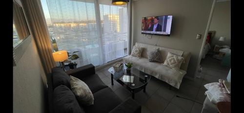 a living room with a couch and a tv at II Cerca de la playa y del centro in La Serena