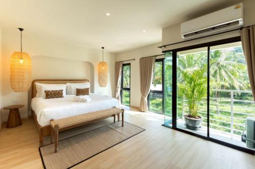 ein Schlafzimmer mit einem Bett und einem großen Fenster in der Unterkunft ELYSIUM Villa Khao Lak in Khao Lak