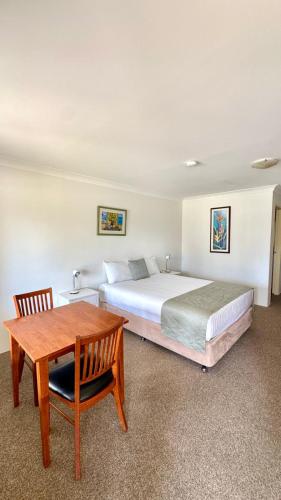 a bedroom with a bed and a wooden table at Marulan Motor Inn in Marulan