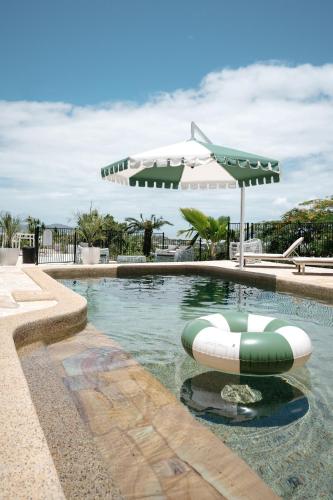 a swimming pool with an umbrella and an inflatable raft at Victoria Street Boutique Hotel Townsville in Townsville