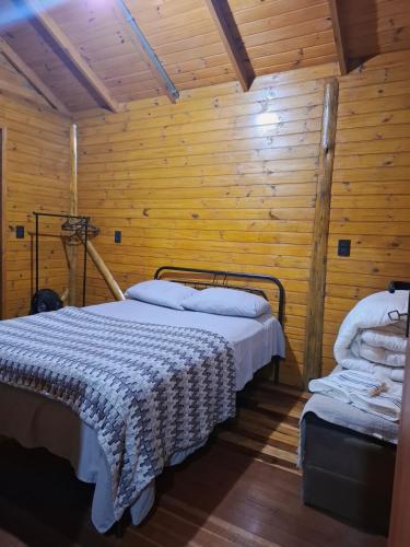 a bedroom with a bed in a wooden wall at Cabana Vermelha Aconchego da Serra in São Francisco de Paula