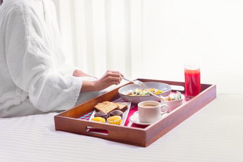 een dienblad met ontbijtproducten en koffie op een bed bij ibis Styles Mysuru in Mysore