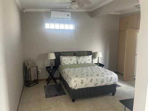a bedroom with a bed and two lamps and a ceiling fan at The College Suite, Mill Park in Gqeberha