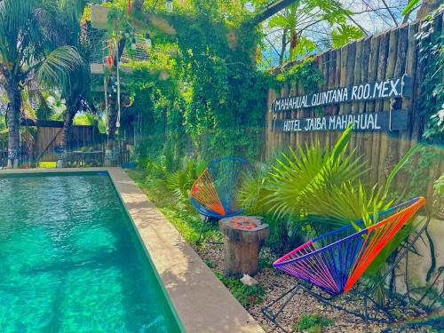 twee stoelen en een zwembad in de tuin bij Hotel Jaiba Mahahual - Adults Only in Mahahual