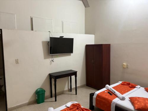 Ein Zimmer mit Fernseher, Bett und Hocker in der Unterkunft Hotel Marios in Espinal