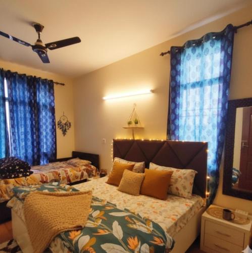 a bedroom with two beds and blue curtains at Exclusive Floor on Manali Expressway for Family in Mohali