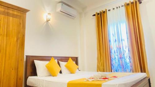 a bedroom with a bed with yellow curtains and a window at Happy Haven in Hikkaduwa