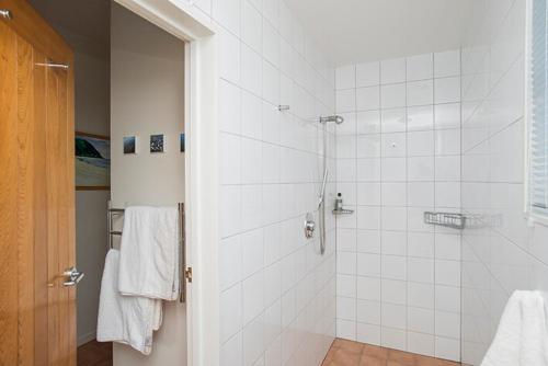 bagno con doccia e piastrelle bianche di Beach loft Makorori a Wainui