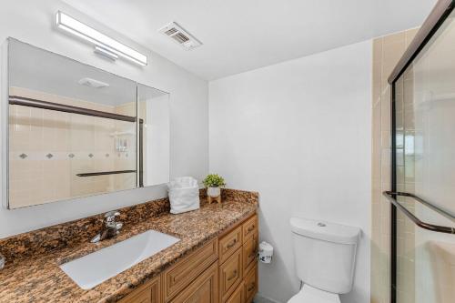 een badkamer met een wastafel, een toilet en een spiegel bij Seabreakers 1 in South Patrick