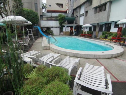 a pool with chairs and a slide in a building at Hotel Supreme in Baguio