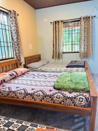 two beds sitting in a room with windows at Malnad cloud homestay Agumbe in Someshwar