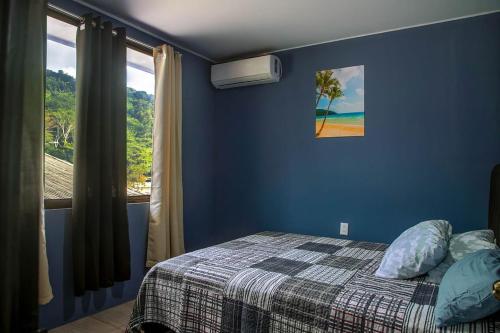 ein Schlafzimmer mit einem Bett und einem Fenster mit einer Palme in der Unterkunft Apartment Steps fr View Los Sueños Adventure Park in Herradura