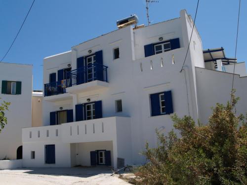 a white building with blue windows on the side of it at Flora Apartments & Studios in Agia Anna Naxos