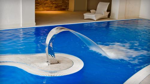 a water fountain in a large blue swimming pool at Hotel Kazimierski Zdrój in Janowiec