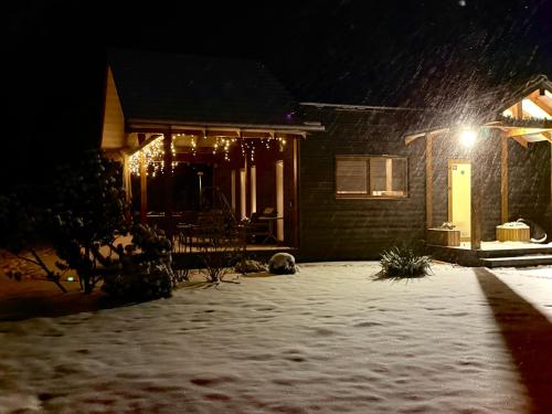 una casa con un cortile coperto di neve di notte di The Flower Nest a Zvejniekciems