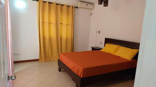 a bedroom with a bed and a yellow curtain at Solrise Villa in Palmar