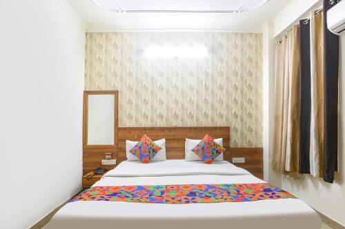 una camera da letto con un grande letto bianco con cuscini colorati di FabHotel Divine a Gurgaon