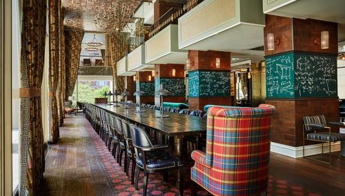 a bar with chairs and a long table in a restaurant at Graduate by Hilton Ann Arbor in Ann Arbor