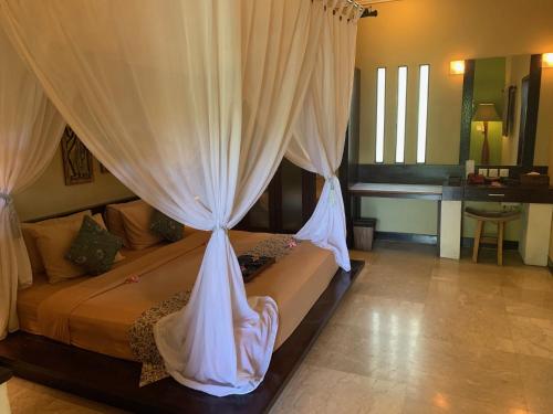 een slaapkamer met een bed met witte gordijnen bij Nike Villas in Sanur