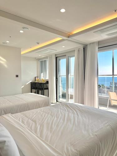a bedroom with two beds and a view of the ocean at Raviens Maison de Hotel in Busan