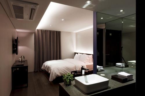 a bedroom with a bed and a sink and a mirror at Seocho H hotel in Seoul