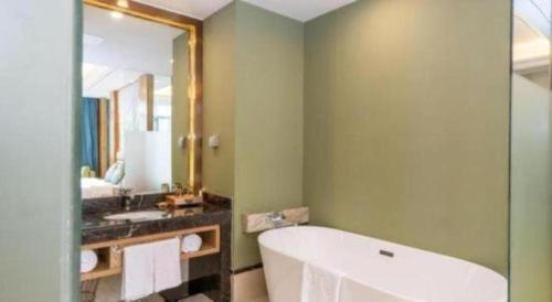 een badkamer met een ligbad en een wastafel bij Ramada by Wyndham Taixing in Taixing