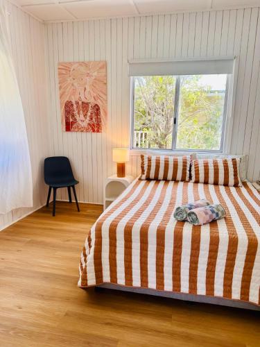 a bedroom with a bed with a striped comforter and a window at Noosa River Gem in Noosaville