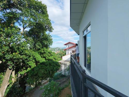 een man op het balkon van een huis bij The Kandy Look Homestay in Kandy