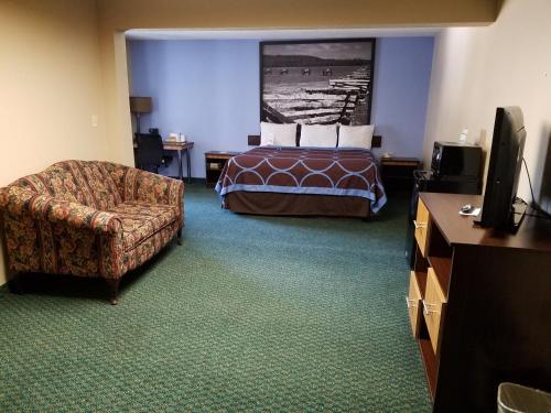 a hotel room with a bed and a chair at Super 8 by Wyndham Bentonville in Bentonville
