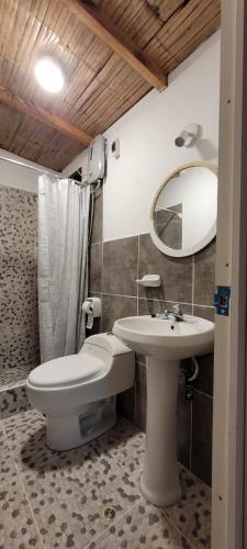 a bathroom with a sink and a toilet and a mirror at Black Marlin - Restaurant and Lodge in Talara