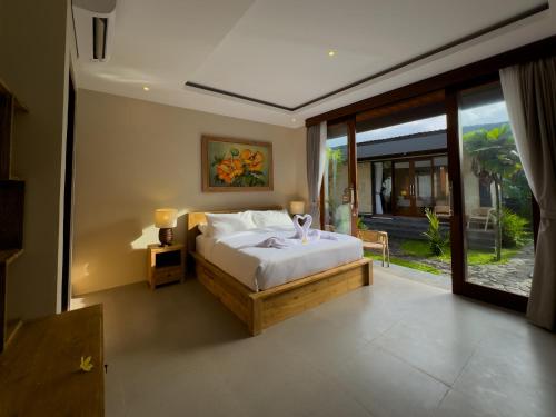 a bedroom with a bed and a large window at Koeluma Bali in Ubud