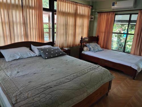 a bedroom with two beds and windows with curtains at Darins House in Nan