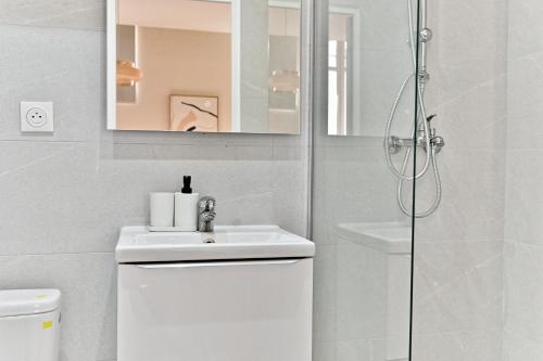 een witte badkamer met een wastafel en een douche bij Cozy air-conditioned studio Pré-St-Gervais in Pré Saint Gervais