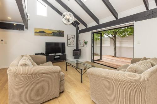 a living room with two couches and a television at Pet friendly downtown Mt Maunganui 3 bedroom home in Mount Maunganui