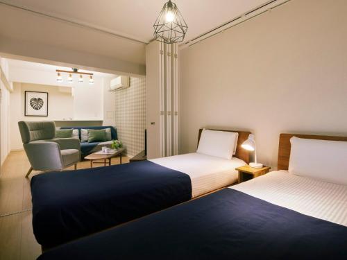 a hotel room with two beds and a couch at KARIO Sasazuka in Tokyo