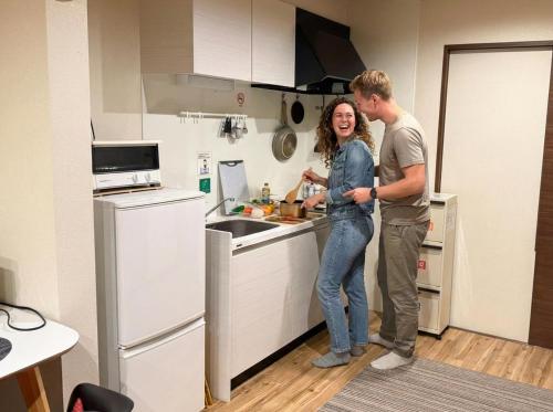 a man and a woman standing in a kitchen at Vieuno Hida Takayama -Live Locally in Cozy Rooms near Takayama Station! in Takayama