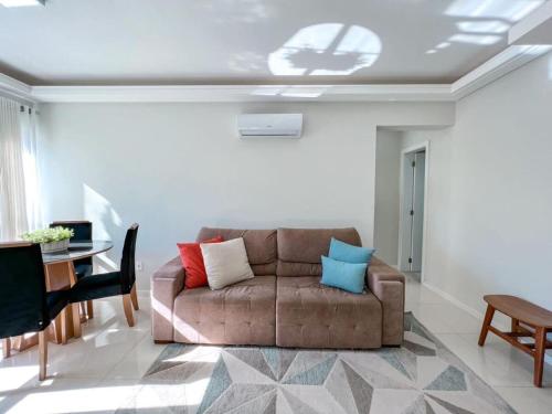 ein Wohnzimmer mit einem braunen Sofa und einem Tisch in der Unterkunft Apartmento próximo ao mar in Capão da Canoa