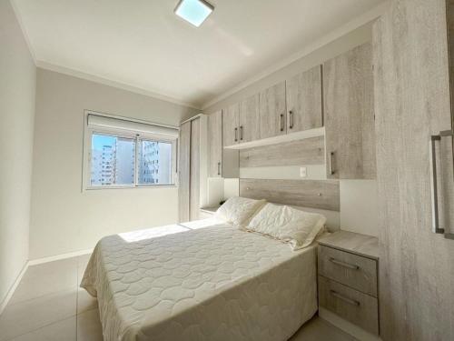 una camera da letto bianca con un letto e una finestra di Apartmento próximo ao mar a Capão da Canoa