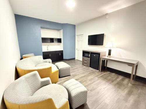 a living room with chairs and a table and a desk at Baymont by Wyndham Tallahassee in Tallahassee