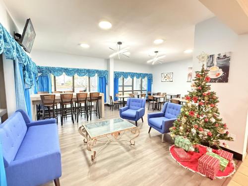 a living room with a christmas tree and blue chairs at Baymont by Wyndham Tallahassee in Tallahassee